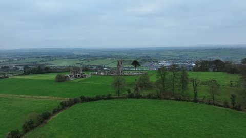 Hill of Slane, County Meath, Ireland, January 2022. Drone orbits the ruined friary church at a higher altitude from the north with Slane town in the background.