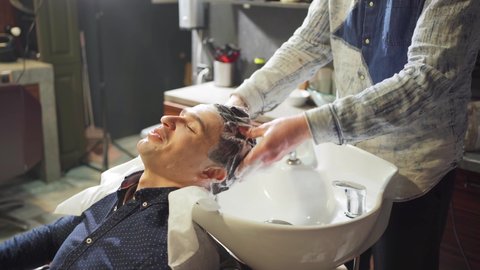 a brunet man washes hair with a hairdresser in a barbershop. beauty salon for men. scalp and hair care products. men's cosmetics.