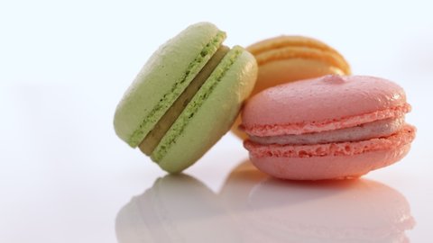 Multicolor macarons , french macaroon, greedy pastry. French dessert sweets colored macaroons cookies arranged on a while plate rotating. Macarons on white reflective glass, sweet tasty desserts