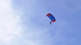 Parachutist Flies on a Paraglider in Blue Sky and Lands on Green Grass. Single, Self jump. Paragliding. Skydiving in clear weather. Extreme sport. 4K. Slow motion.