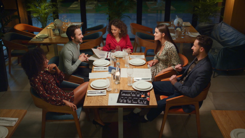 Multiethnic friends celebrating have fun in night fancy restaurant. People talking together at evening luxury cafe table. happy group gathering enjoying friendship in bar. Dining concept. Royalty-Free Stock Footage #1087774673