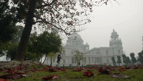 Timelapse video of Victoria Memorial of Kolkata in winter morning with leafless tree and red fallen leaves on the grasses of the lawn. HD stock footage. West Bengal, India