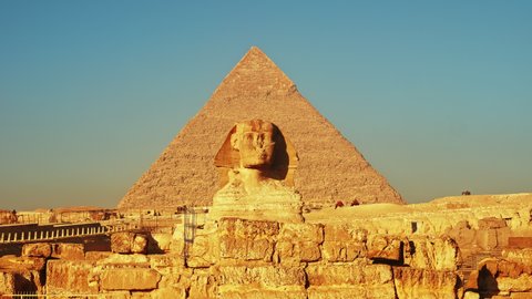 Pyramid of Khafre or Chephren and Great Sphinx of Giza. Ancient Egyptian mortuary temple construction from limestone blocks, a statue of mythical creature. Camels moving along the road. Sunny day