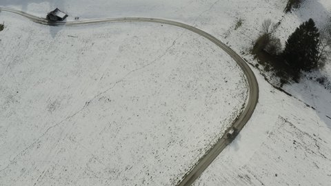 Aerial view following a tractor driving in middle of snowy fields in Bavaria, Germany - tilt, drone shot