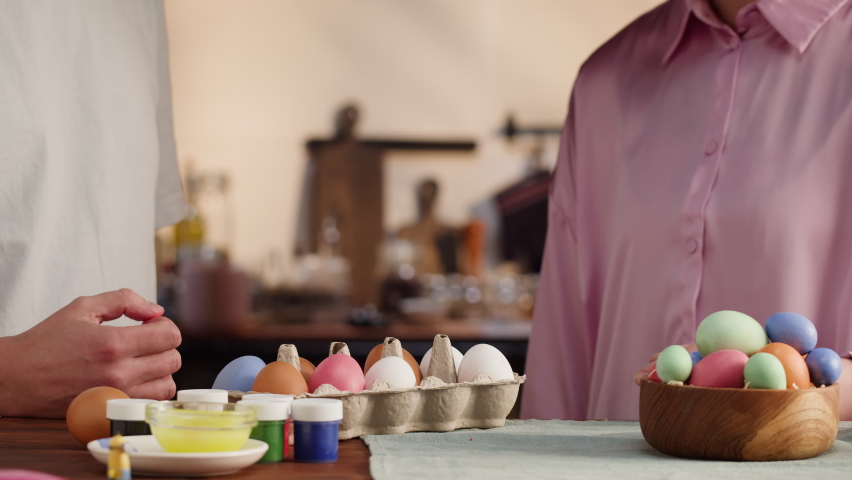 Happy Easter holiday. Man and woman beating colored eggs close-up. People preparing for Easter, painting and decorating eggs. Christian celebration, family traditions.