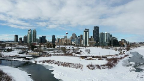 Moving drone shot of Calgary skyline with Bow River in foreground.  Winter