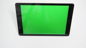 A man's hand presses play button on a tablet with a green screen. Index finger of the left and right hand starts watching videos on your Tablet-PC.