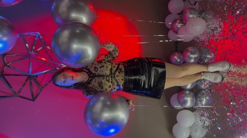 PETERSBURG, RUSSIA - NOVEMBER, 4, 2021: Vertical video. Young beautiful caucasian woman dancing at the party at nightclub. Sexy transparent bodysuit, latex leather short mini skirt and harness wings.