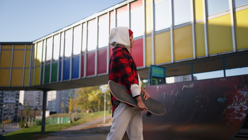 Young multiracial woman outdoors in the city, with skateboard looking at camera.