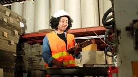 One African American female industrial worker with a hard hat checks the machine and writes inspected engine parts. Professional works in a paper manufacturing factory, maintain production equipment. - Powered by Shutterstock - Get 15% off with code: PIKWIZARD15