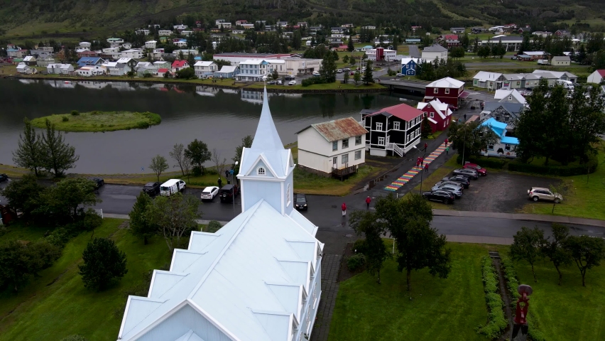 Beautiful cinematic aerial view of the town of Seydisfjordur and its Blue church and rainbow street pier and cruise ships