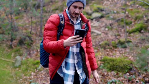 Young caucasian backpacking solo travel lost in the natural forest looking for maps direction from 5g network smartphone device. strong signal unlimited internet data in remote countryside