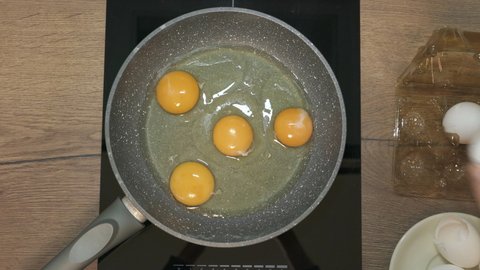 Fresh eggs break in hot frying pan on stove. Fried eggs in non-stick pan.