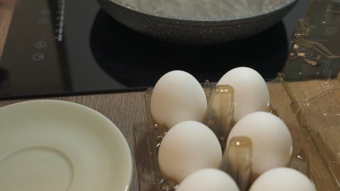 Fresh eggs break in hot frying pan on stove. Fried eggs in non-stick pan.