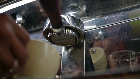 Espresso shot pouring in coffee cup from bottomless portafilter on coffee machine