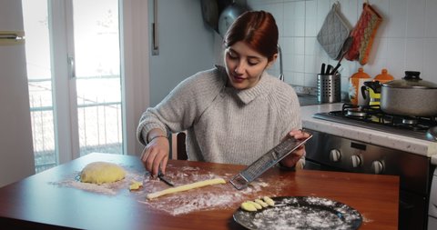 Young girl cutting out shapes for homemade gnocchi on the kitchen table