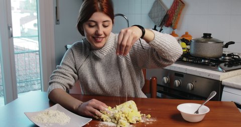 Girl is putting flour into potato dough for homemade gnocchi