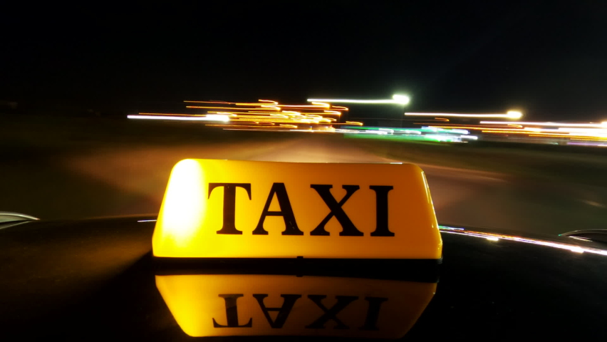 Hyper lapse footage of taxi driving on city streets at night, close up of illuminated taxi cab sign mounted on car rooftop Royalty-Free Stock Footage #1087802623