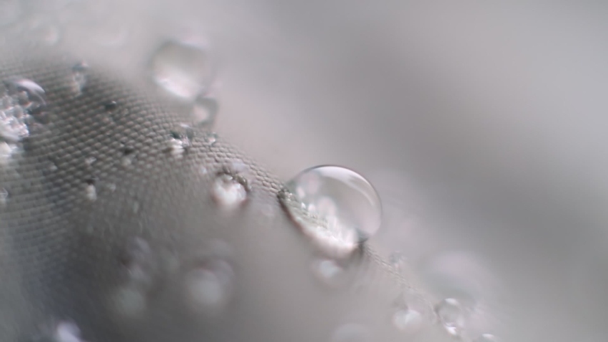 Slow Motion Shot of Water Splashing on waterproof fabric. water beading on fabric. Waterproof coating background with water drops. soft focus, blur Royalty-Free Stock Footage #1087805097