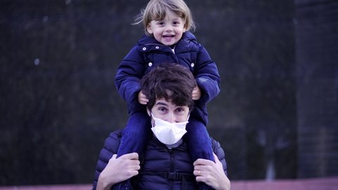 Toddler child on father shoulders wearing covid mask