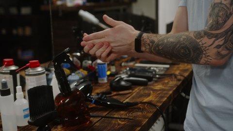 Barber treats hands with alcohol solution before client haircut in beauty salon