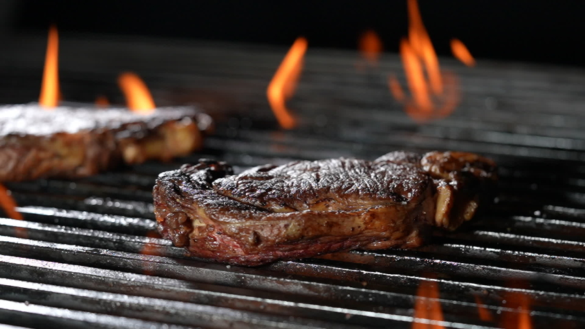 Cooked juicy steak meat beef sprinkled with seasoning on a flaming grill. slow motion Royalty-Free Stock Footage #1087811207