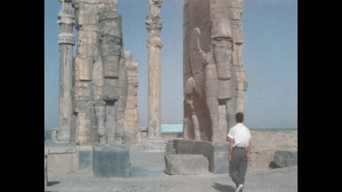 1960s: Man approaching stone sculptures. Text on stone blocks. Person looking at stone ruins. Hand holding clapperboard. Stone carvings.