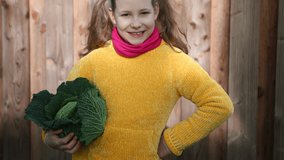 4K video of funny little girl with two pigtails in yellow smiling with fresh autumn harvest in sunny rural garden