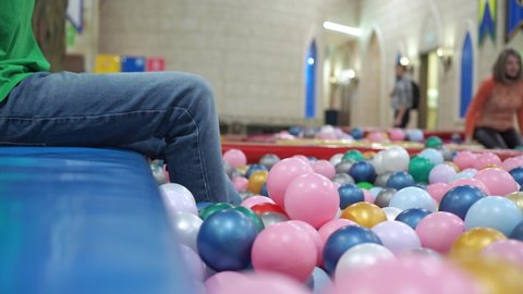 a boy plays with his feet with balls in a pool with plastic balls. children's entertainment center