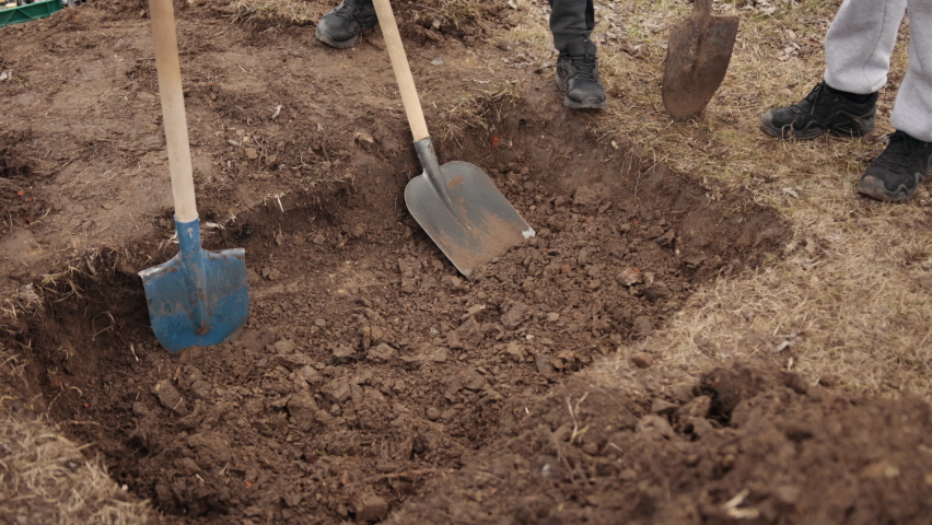 Freshly dug grave tool at cemetery, a close-up. Grave, top view, just been digged, spade by edge. Digging. Pit in ground. Shovel lies in pit. Digging hole with spade in field Royalty-Free Stock Footage #1087816267