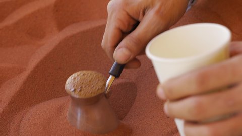 Coffee prepared on street in traditional Arabic way, cezve or ibrik (small Turkish coffe pot) is placed in red hot sand until liquid boils