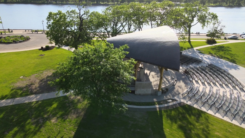 Bird view of newly completed shelter over stage venue in park along the Mississippi River. New concrete and benches installed. Sun reflecting off the water. 