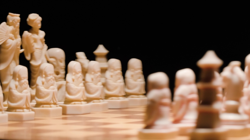 Close up Ivory chess pieces spinning on chessboard. Black background