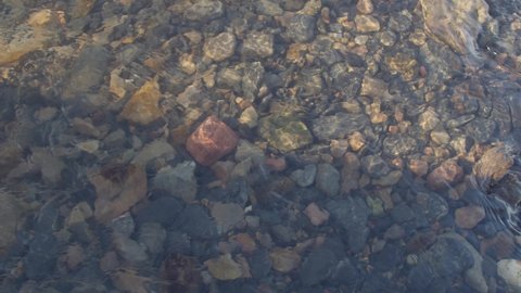 Stones in different colours and shapes in a watercourse at golden hour.