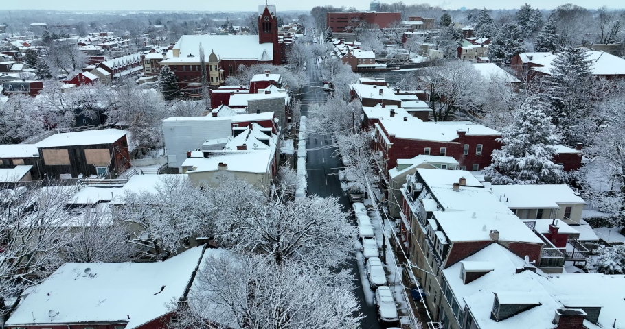 Aerial reveal above street during winter snow. Night shot in evening. Reverse aerial dolly shot.