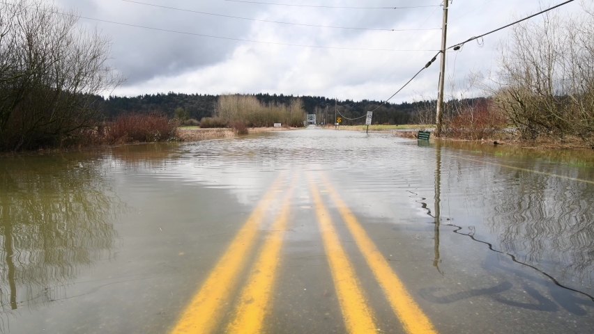 Flooded road in the Snoqualmie Valley of Western Washington with double yellow lines submerged under the water