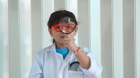 asian kid girl in red glasses is playing a doctor and check heart toy.