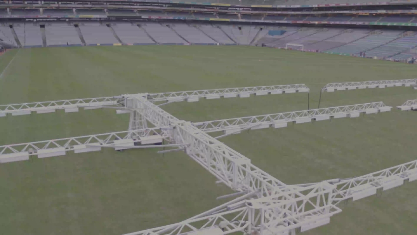 Flying though Croke Park unveiling the green field of the stadium, it reaches the edge of the court allowing the drone shot to pan up to the empty arena seats.