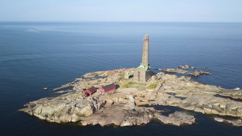 Aerial view of a isolated lighthouse on a rocky island in the middle of the sea.