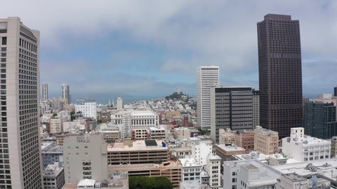 Aerial rising shot of Coit Tower and Alcatraz Island in the distance from Union Square in Downtown San Francisco with some fog. 4K
