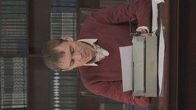 Vertical Video. Focused Male Writer Using Vintage Typewriter for Work, Creating Novel or Article at Home Office