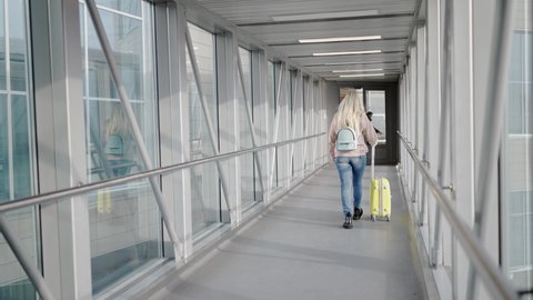 Business woman at the airport goes to the landing of the plane with hand luggage at the train station or at the airport, heading to the boarding gate.