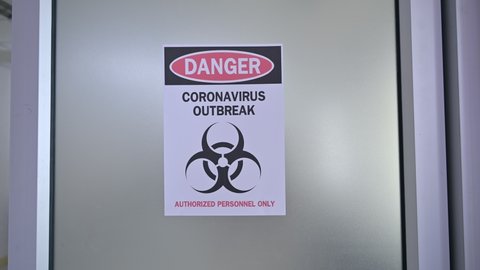 Panning shot of Alert notice paper on the door of danger coronavirus outbreak with biohazard symbol and authorized personnel only in the hospital