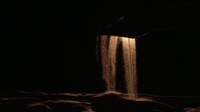 Silhouette of female hand picking up handful of sand and spilling grains of sand from her palm on black background with backlight. Particles of sand pour through fingers in dark. Close up. Slow motion - Powered by Shutterstock - Get 15% off with code: PIKWIZARD15