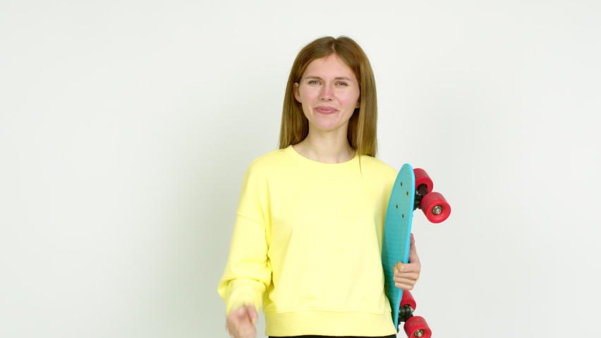Young woman holding roller skates and celebrating a victory over isolated background