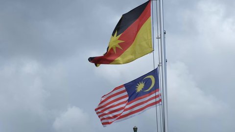 A handheld footage of Sarawak flag waving with Malaysia flag insight."
