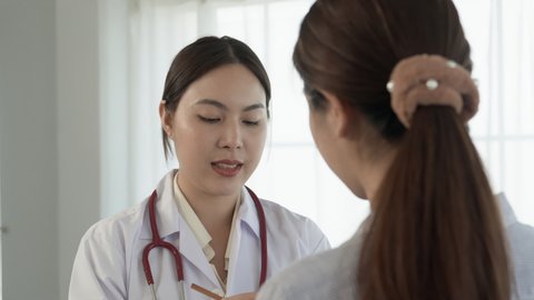 4K 50fps, long-haired Asian female doctor stands inquiring about the patient's condition and talking with a serious face.