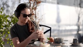 woman is listening to music and watching video by smartphone and headphones when had breakfast