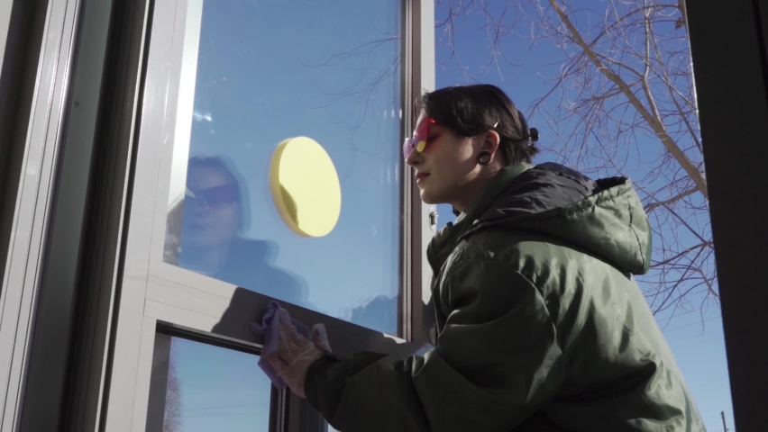 The cleaning lady diligently washes the glass door from the outside.