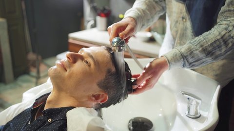 a brunet man washes hair with a hairdresser in a barbershop. beauty salon for men. scalp and hair care products. men's cosmetics.